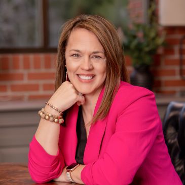 Smiling woman in a pink blazer.