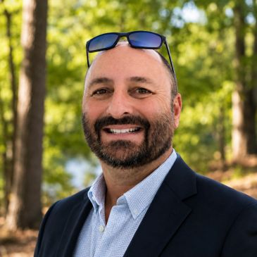 Smiling man with sunglasses on head outdoors.