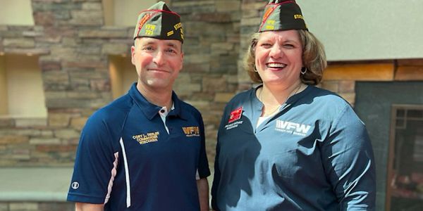 Two veterans wearing VFW caps and shirts.