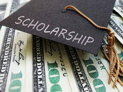Graduation cap with 'Scholarship' written on money.