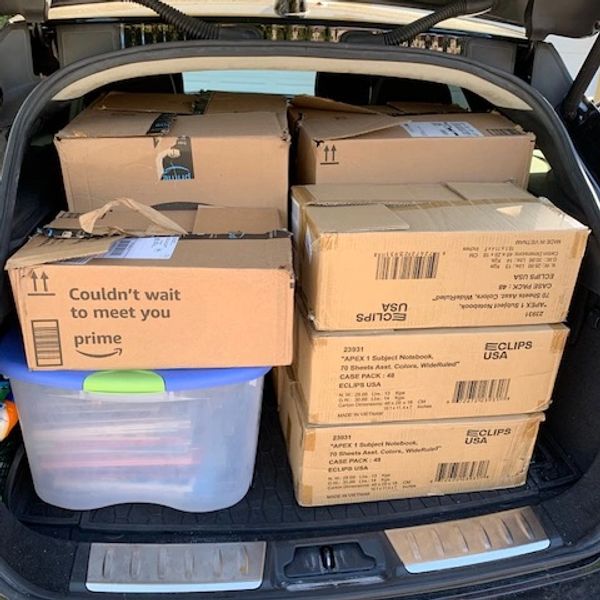 Packed car trunk with cardboard boxes and a plastic container.