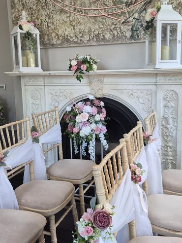 Elegant floral wedding decoration on chairs and fireplace.