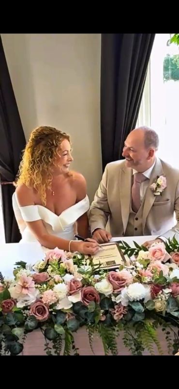 Bride and groom signing marriage documents with smiles.