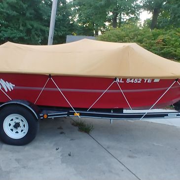 Tan Aqualon ski boat cover with rope and loop fittings attached to trailing with rope straps.