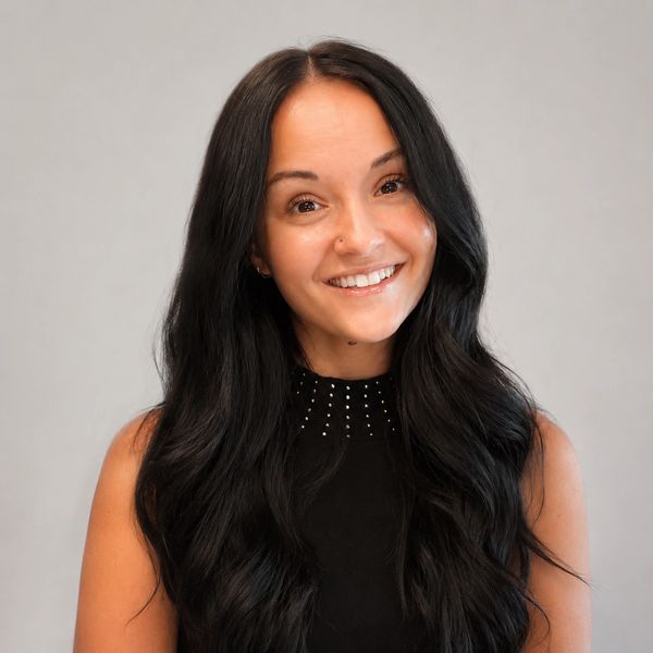 Smiling young woman with long black hair and a black studded top.