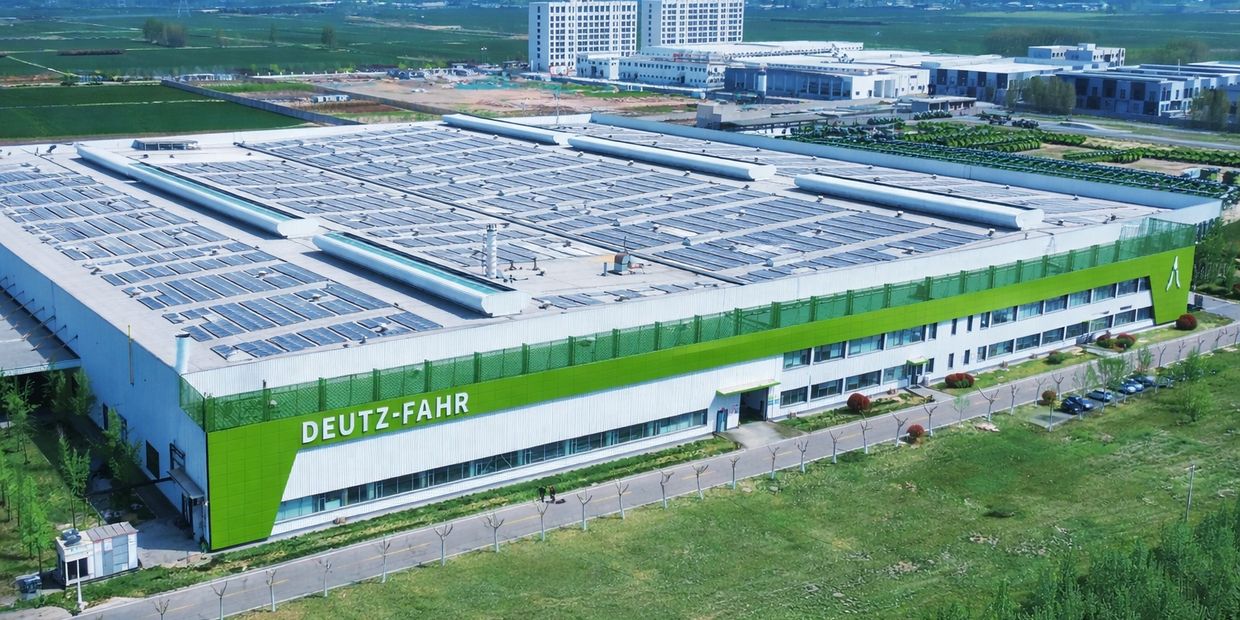 Vista aérea de una gran planta industrial de maquinaria agrícola con techos cubiertos de paneles sol