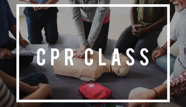 People learning CPR on a training mannequin in a CPR class.