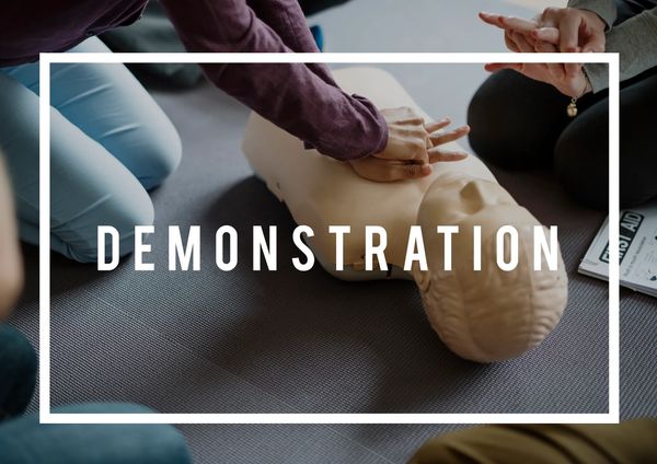 Hands demonstrating CPR on a training mannequin during a safety session.