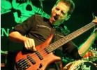 Musician playing an electric bass guitar on stage.