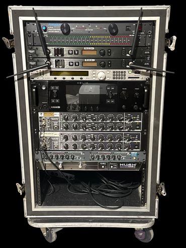 Professional audio equipment rack with wireless receivers and signal processors.
