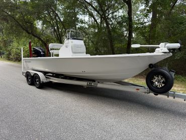 White boat on a trailer in a wooded area.