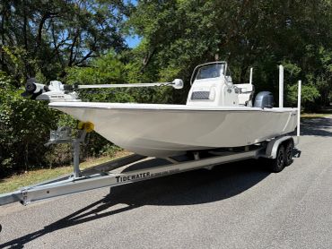 A white fishing boat on a trailer parked on a road.