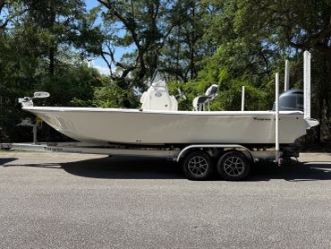 White fishing boat on a trailer parked on the street.