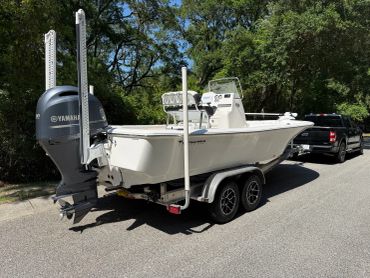 White motorboat on trailer hitched to a black pickup truck.