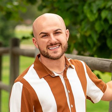 Smiling bald man outdoors in a striped brown and white shirt.