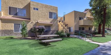 Apartment complex with picnic tables and greenery.