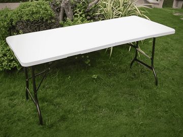 A white folding table set up outdoors on green grass.