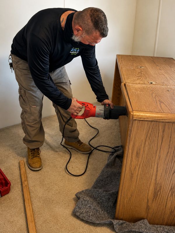 Tony cutting apart a large office desk for junk removal in Edgewater, Fl.