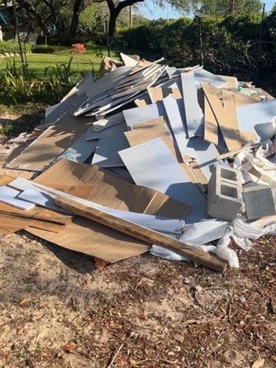 Pile of construction debris and cardboard in an outdoor area.