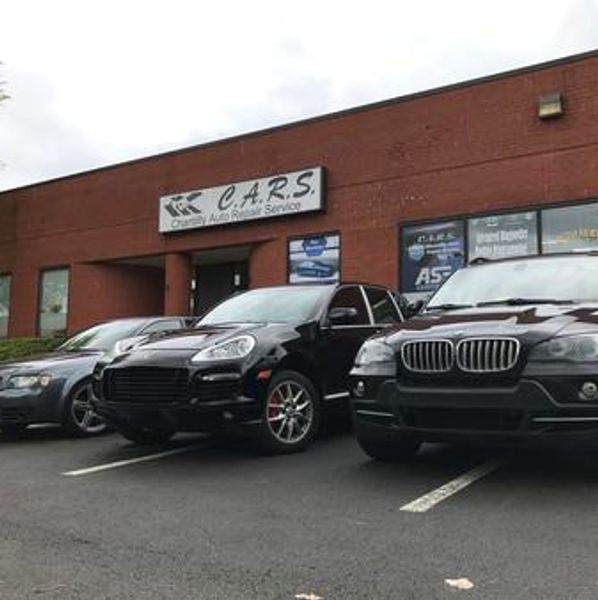 Three cars parked outside a car rental service building with a sign reading "C.A.R.S." 