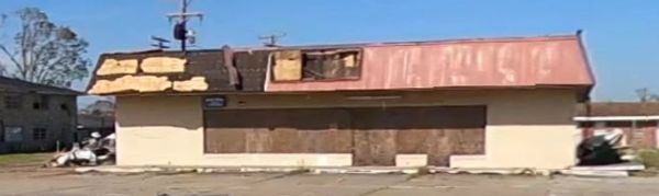 Abandoned building with boarded-up windows and a damaged roof.
