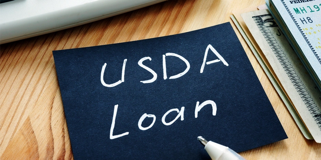 Navy blue post it note with USDA Laon written on it next to a stack of cash