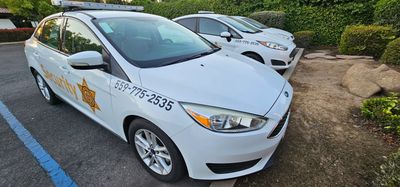Two white security patrol cars parked side by side near greenery.