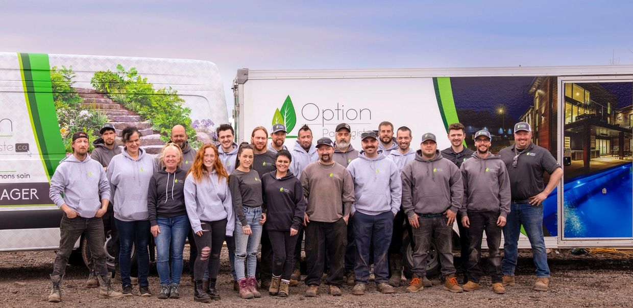 Équipe Option Paysagiste devant leurs camions de service d'entretien paysager.