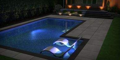 Une piscine avec contour en dalle de béton avec de l'éclairage extérieur