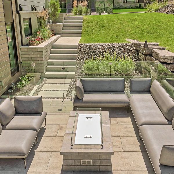 Cour arrière aménagée avec terrasse moderne, foyer au propane, escalier et muret de pierre