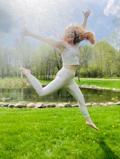 A picture of Coach Katie leaping in the air while smiling. 