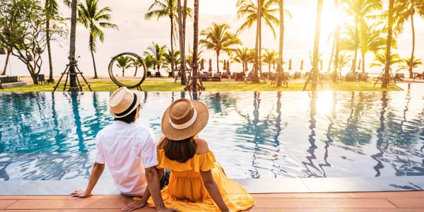 couple enjoying the view as they stick their feet in the pool of the resort overlooking the ocean