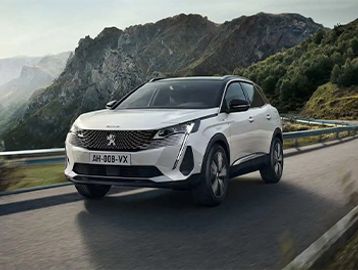 White Peugeot SUV driving on a mountain road.