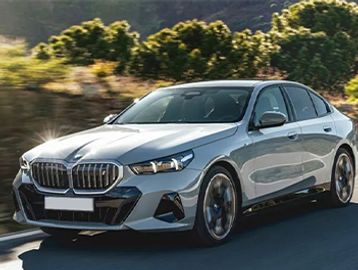 A sleek silver BMW driving on a scenic road with trees in the background.