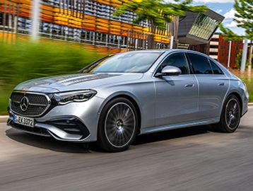Silver Mercedes-Benz sedan driving on a city street.