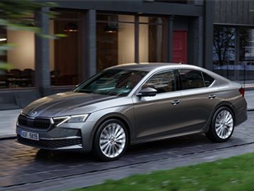 A sleek silver sedan parked on a city street near a modern building.