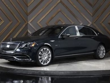 Black luxury Mercedes-Benz sedan displayed indoors with stylish background.