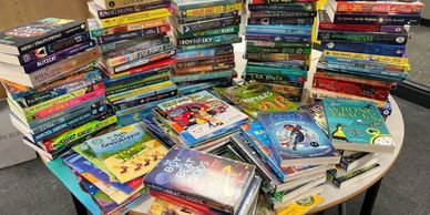 A table covered with numerous colorful children's books arranged in stacks.