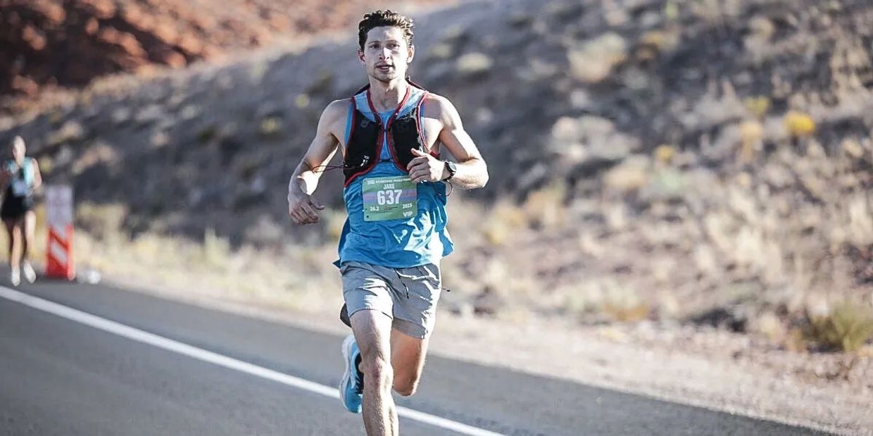 Man running a marathon on a desert road.