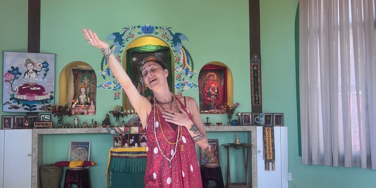 A woman in a red dress performs a dance in a colorful spiritual shrine.