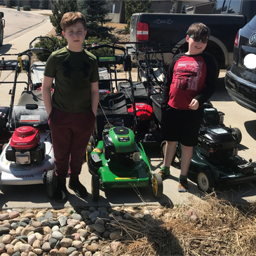 The Small Engine Flippers owners standing with the push mowers they repaired and put on the market.
