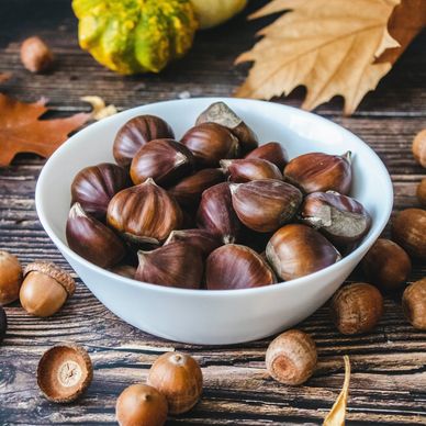 castagne su un tavolo con foglie di autunno e zucche in prospettiva dietro