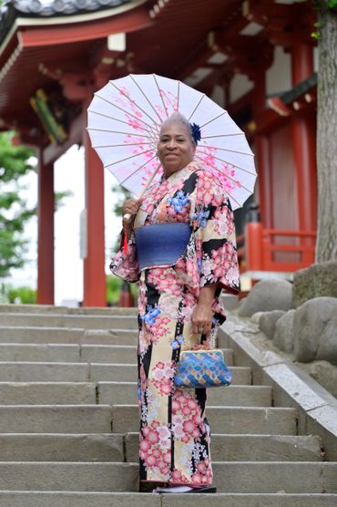 Woman in floral kimono holding a parasol on stone steps.