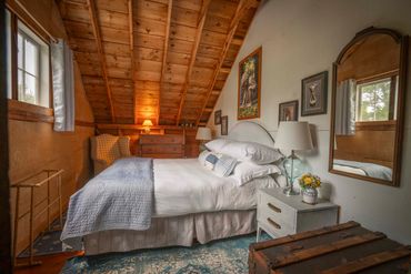 Cozy attic bedroom with wooden ceiling and soft lighting.