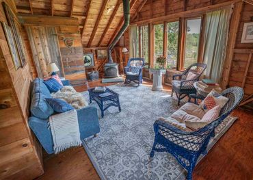 Cozy rustic living room with blue wicker furniture and a wood stove.