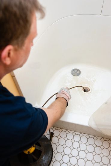 a man cleaning bathtub drain 