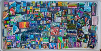 A selection of dichroic glass on a tray in multiple designs ready for the kiln. 