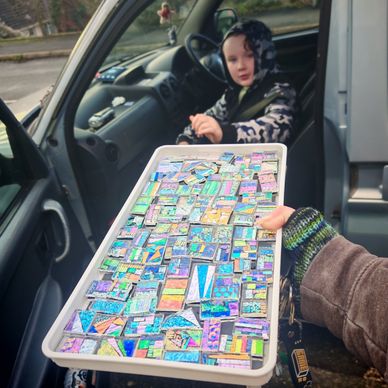 Passing the dichroic glass designs on a tray to Zander who is in the car