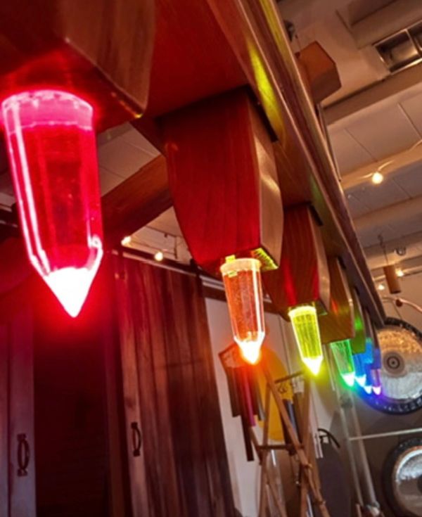 Colorful pencil-shaped lights hanging from a wooden fixture.