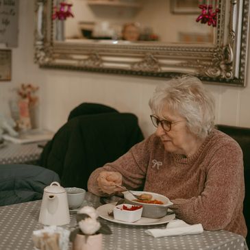 Older woman enjoying a meal in a cozy cafe.